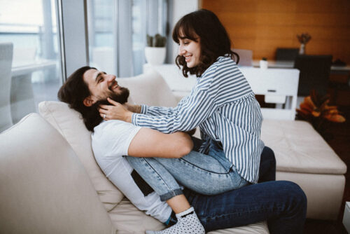 A couple where one person is sitting on the others lap and they are practicing communicating about sex.
