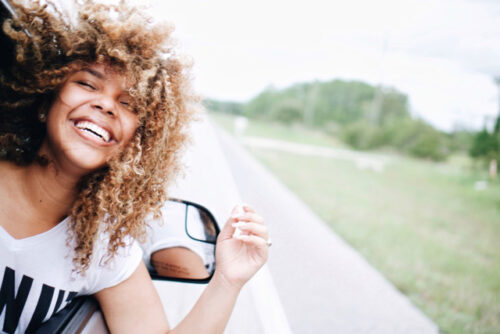 A person leaning out the window of a vehicle, laughing.