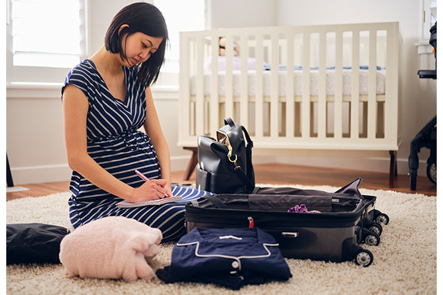 pregnant woman packing bag on floor