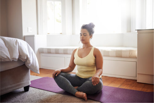 A person practicing a type of meditation in their bedroom.