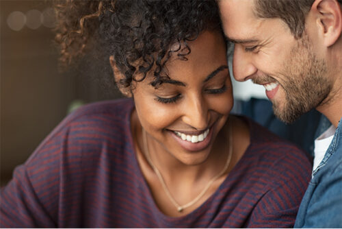 A couple standing close together and smiling while discussing the definition of consent.
