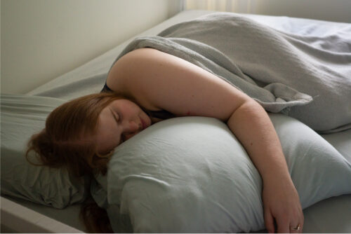 A woman sleeping in bed sideways because it’s her bedtime ritual to help her sleep better.
