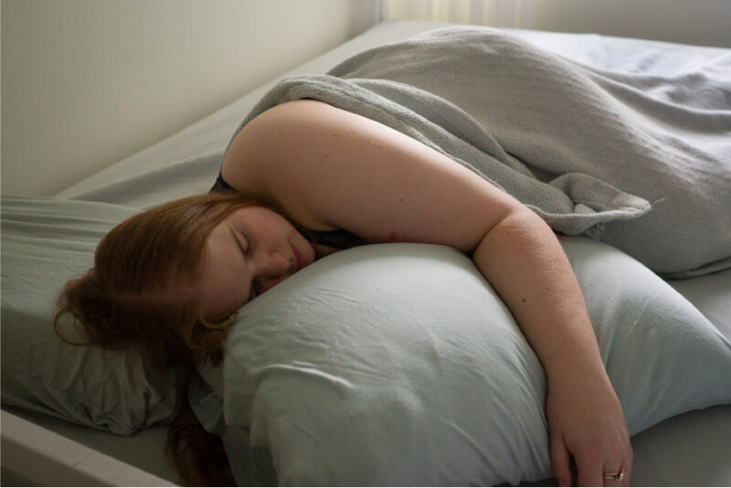 A woman sleeping in bed sideways because it’s her bedtime ritual to help her sleep better.