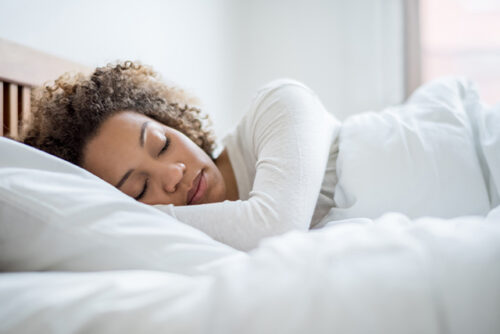 A woman who understands the importance of sleep taking a day time nap in her bed.