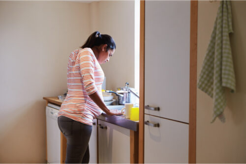 Woman standing at the sink in pain
