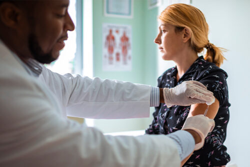 Doctor examining a patient while she wonders if vaccines are safe.