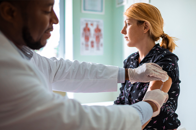 Doctor examining a patient while she wonders if vaccines are safe.