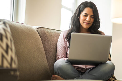 Women using her laptop while sitting on a couch researching sexually transmitted infections.