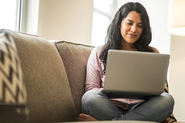 Women using her laptop while sitting on a couch researching sexually transmitted infections.