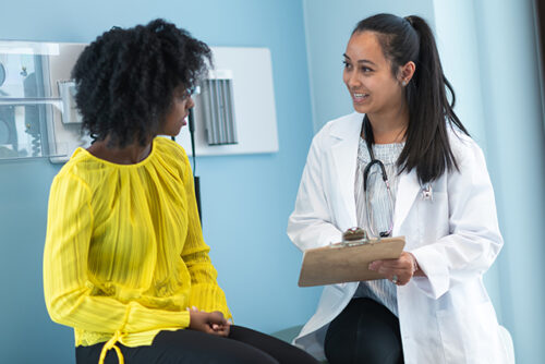 A women in gynecologist office talking to doctor about genital infections.