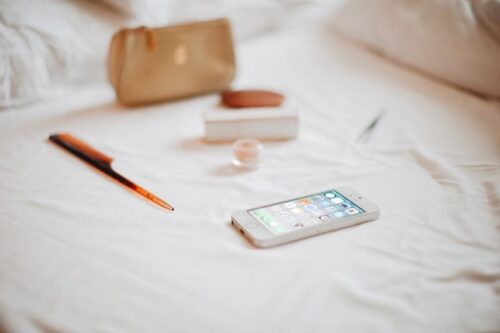 A cellphone, pen, bag, and other items on a bed to represent using Ovia Fertility versus other tools to track your ovulation.