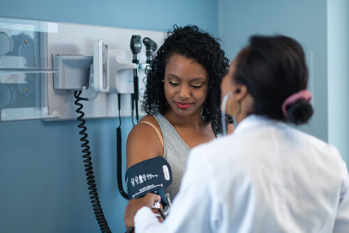 A woman at doctors office getting her blood pressure checked to represent getting a blood pressure tracker.