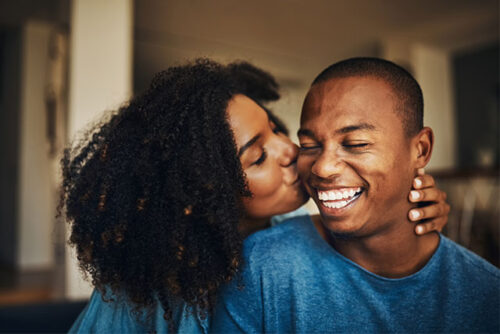 A woman kissing boyfriends cheek.