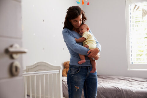 A person holding their newborn baby and wondering 'how long should you wait to get pregnant again?'