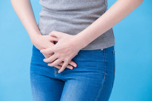 A person holding the area near their uterus to represent endometriosis.