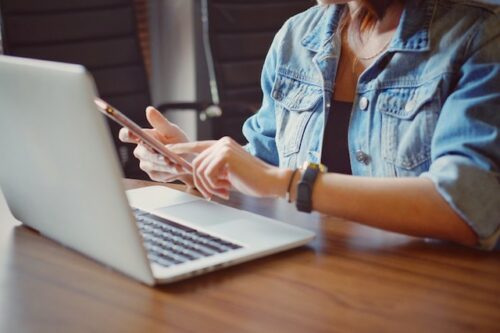 A person on their laptop and cellphone looking up information on how to track fertility at their proliferative phase.