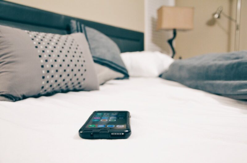 A phone on the bed to represent how to use it to track your luteal phase.
