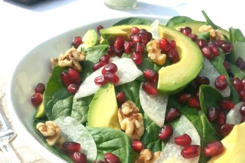 A plate of salad with avocado, pomegranate, and jicama salad with creamy avocado dressing.