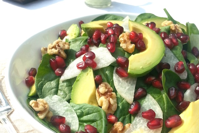 A plate of salad with avocado, pomegranate, and jicama salad with creamy avocado dressing.