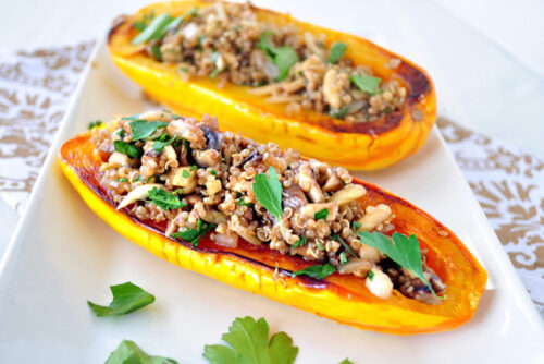 Two stuffed delicata squash on a plate from a recipe.