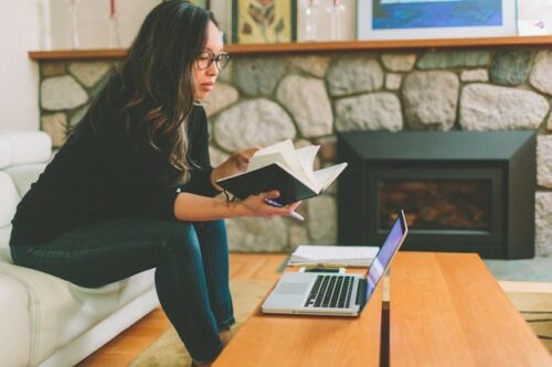 A person reading a book and using their laptop to look up information about their infertility consultation.