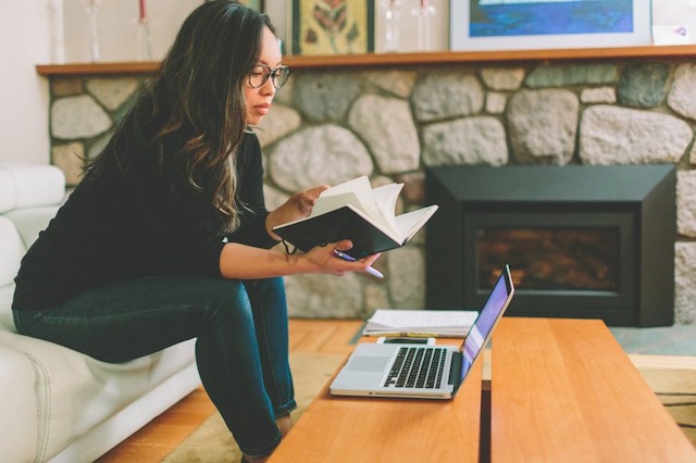 A person reading a book and using their laptop to look up information about their infertility consultation.
