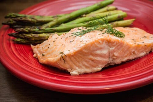 Red plate with salmon and asparagus made from this salmon en papillote recipe.