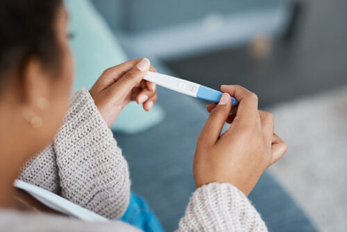 A woman looking at her pregnancy test and wondering how to take it.
