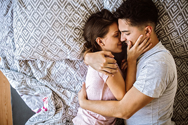 A couple in bed holding each other close.