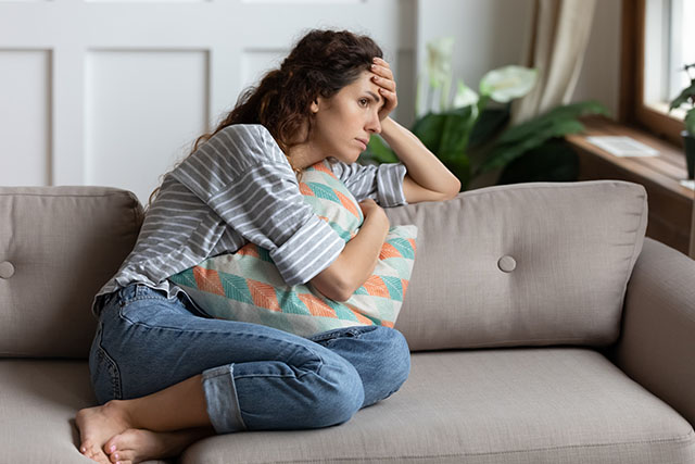 A woman sitting on couch wondering if antidepressants affect fertility.