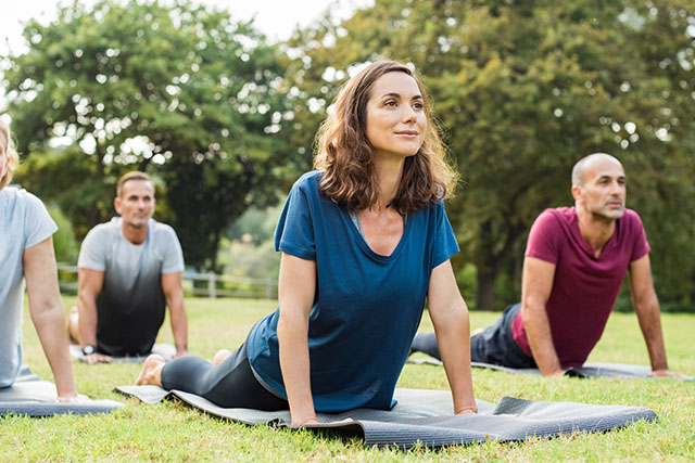 A woman doing yoga in the park as a way to prepare for pregnancy.