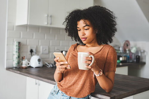A woman looking at phone thinking about tracking her ovulation cycle.