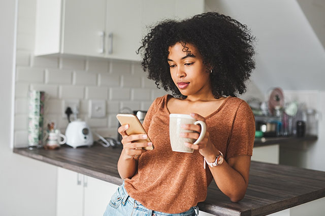 A woman looking at phone thinking about tracking her ovulation cycle.