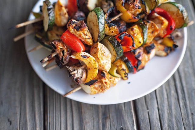 A plate of chicken and vegetable skewers.