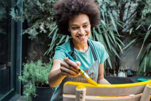 A woman painting chair yellow.
