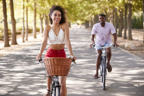 A couple riding bikes through a forest.