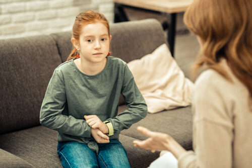 Child sits on the couch facing an adult who is out of view