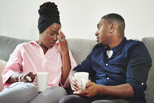 Couple sits on couch in conversation