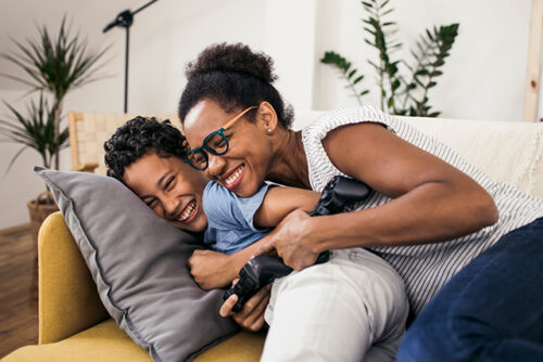 Mom and son snuggle on the couch, smiling.