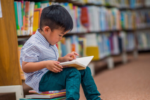 little boy looks at a book while seated