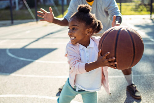 Child holds a basketball on the court