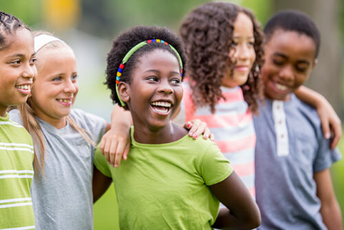 Group of children smile with their arms around each other