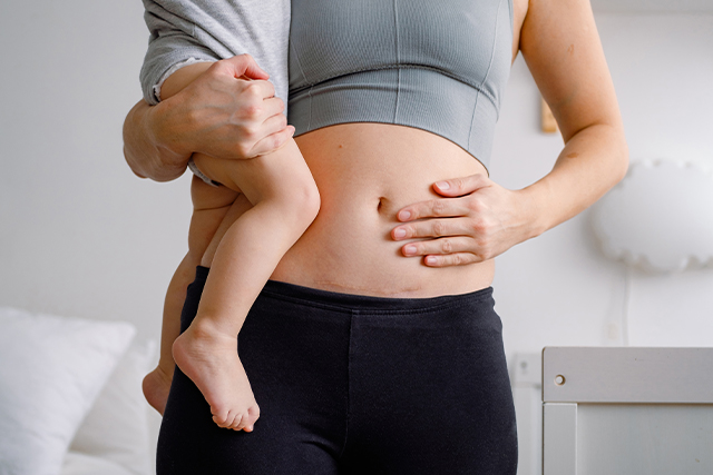 Person holding baby and touching abdomen