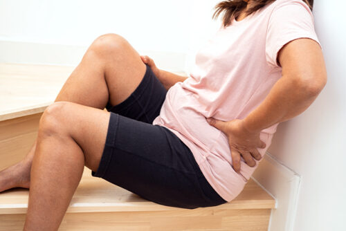 person on stairs holding their side.