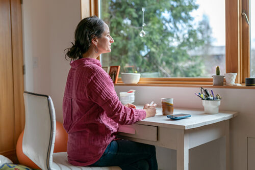 woman sitting at desk looking out her window