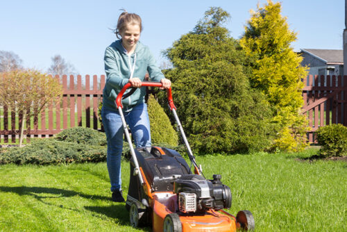 Girl smiles as she mows the law