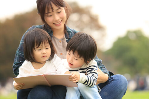 woman reads book to two kids