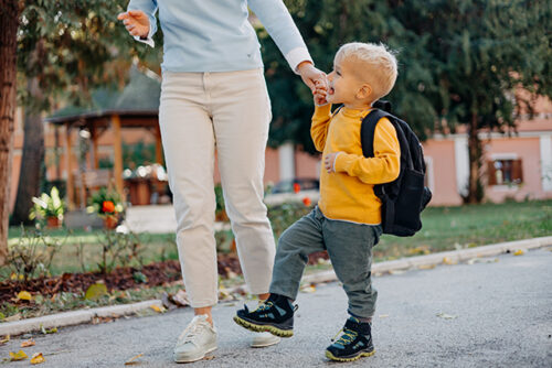 child with backpack and parent walking