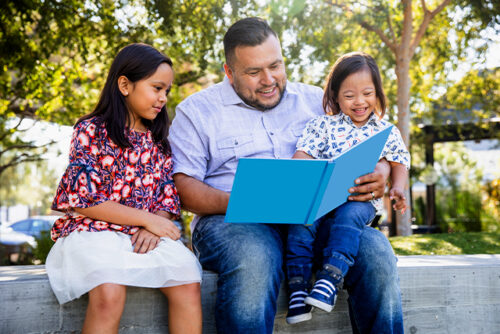 A man reads a book to two children
