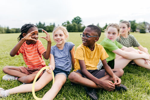 young group of kids sitting and talking on grass